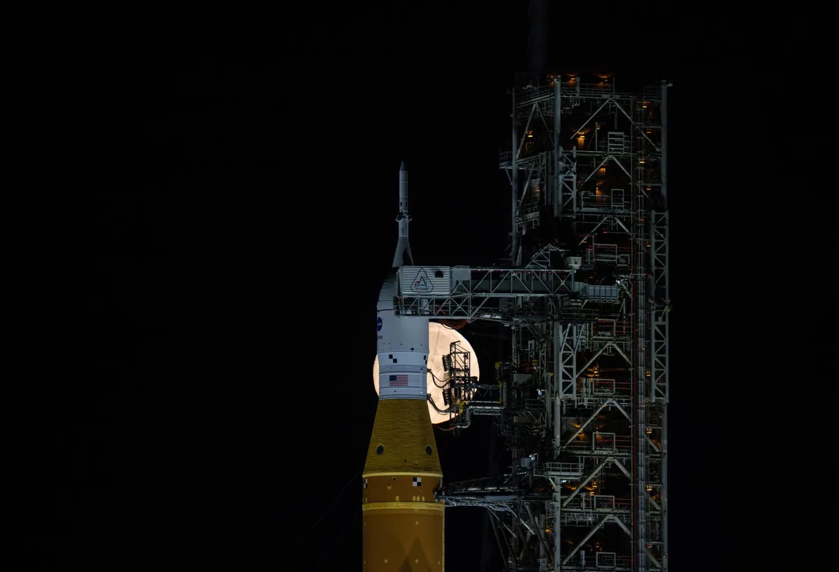 The full moon rising over Artemis II at Launch Pad 39B.